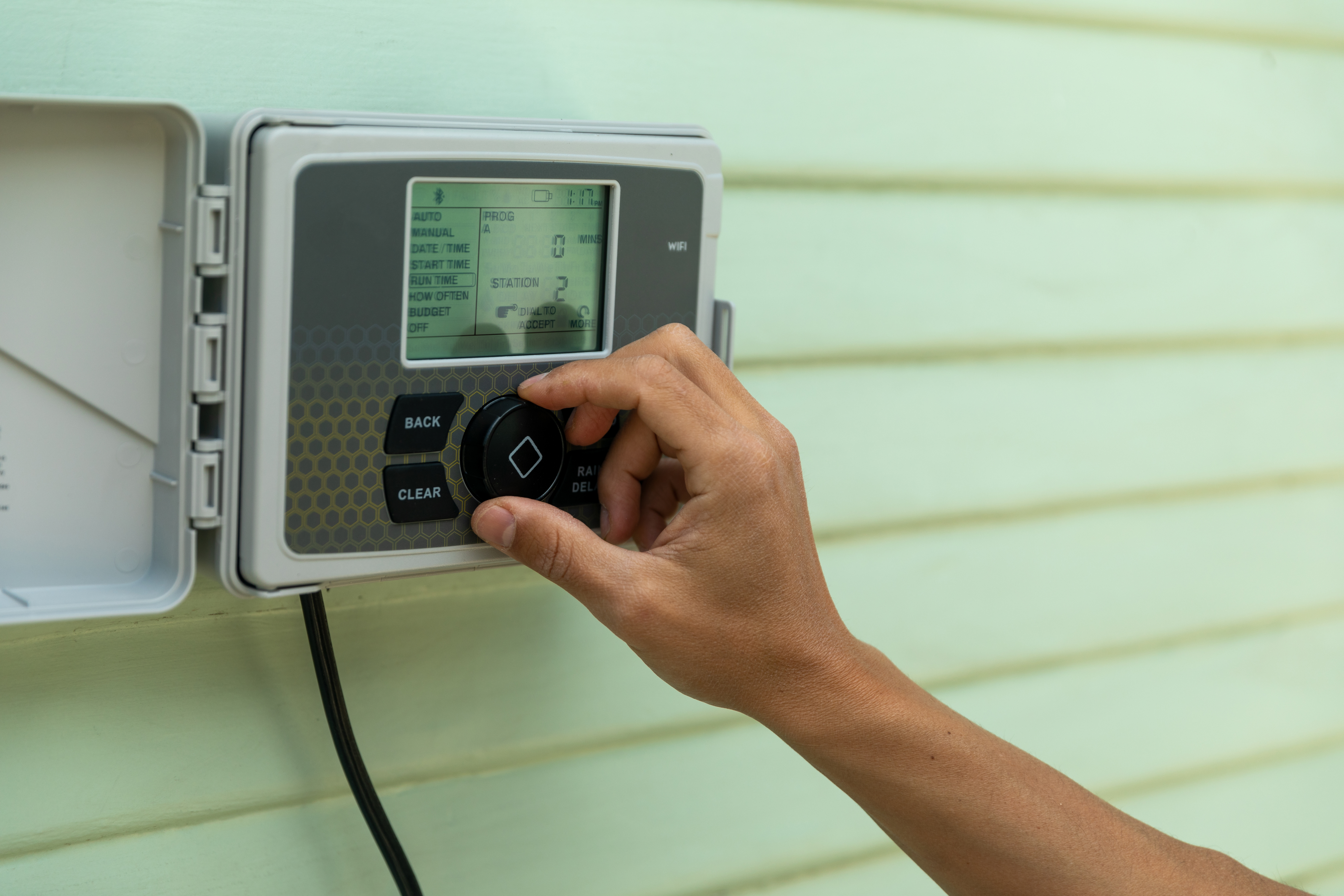 A person adjusts a smart sprinkler controller provided as a part of a water conservation program