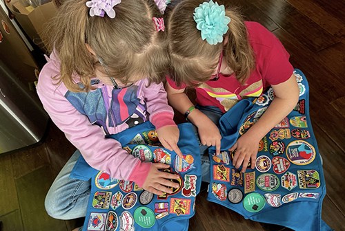 Daisy Girl Scouts showing eachother the patches on their vests