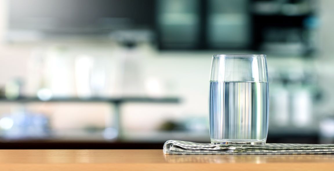 Un vaso de agua pura colocado sobre una mesa.