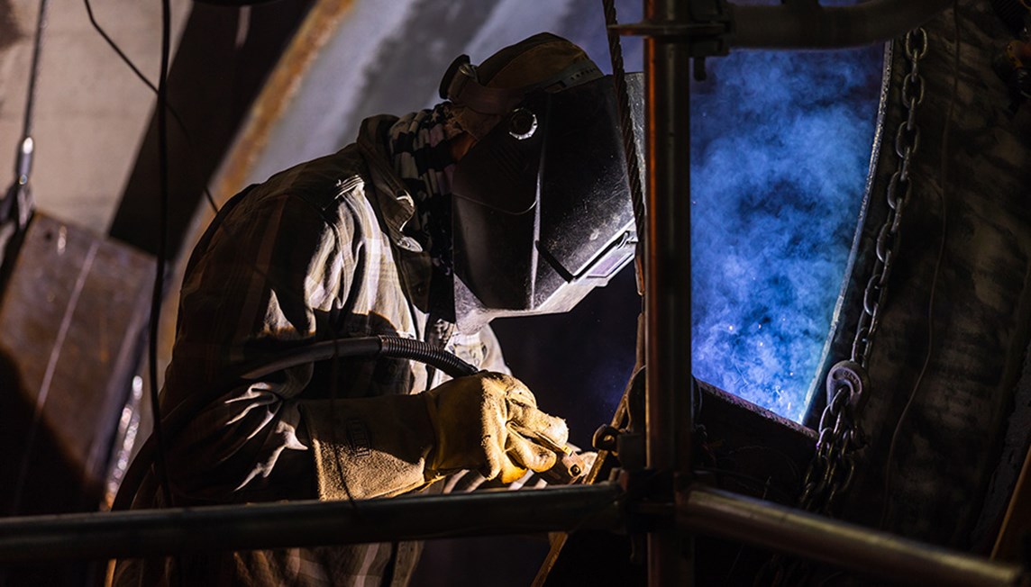 A welder attaching metal sheets to a frame