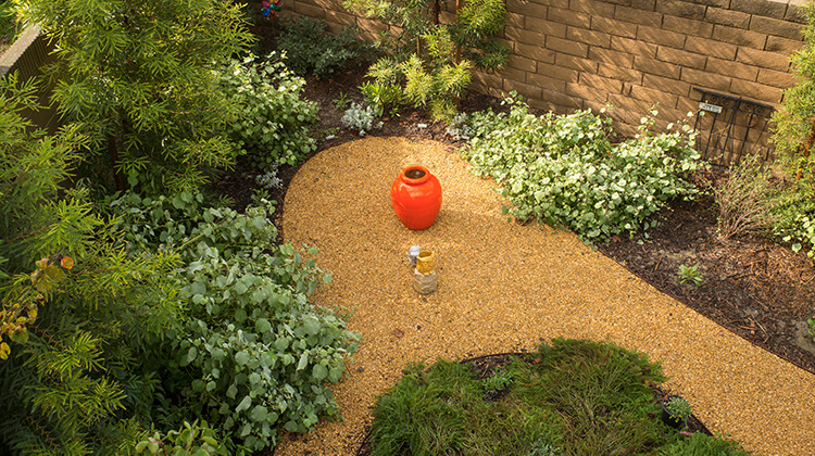 Photo of a drought-tolerant garden with a planter in the middle of the garden path.